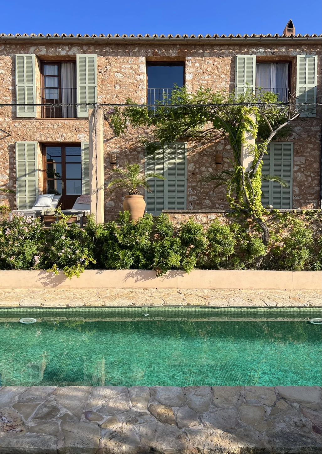 Stenhuset på Mallorca, med naturstensfasade og grønt basseng